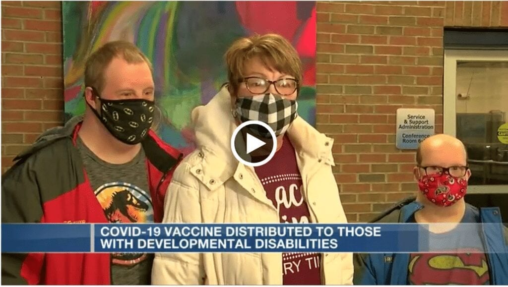 Three people stand with masks on. A caption reads: COVID-19 Vaccine distributed to those with developmental disabilities. 