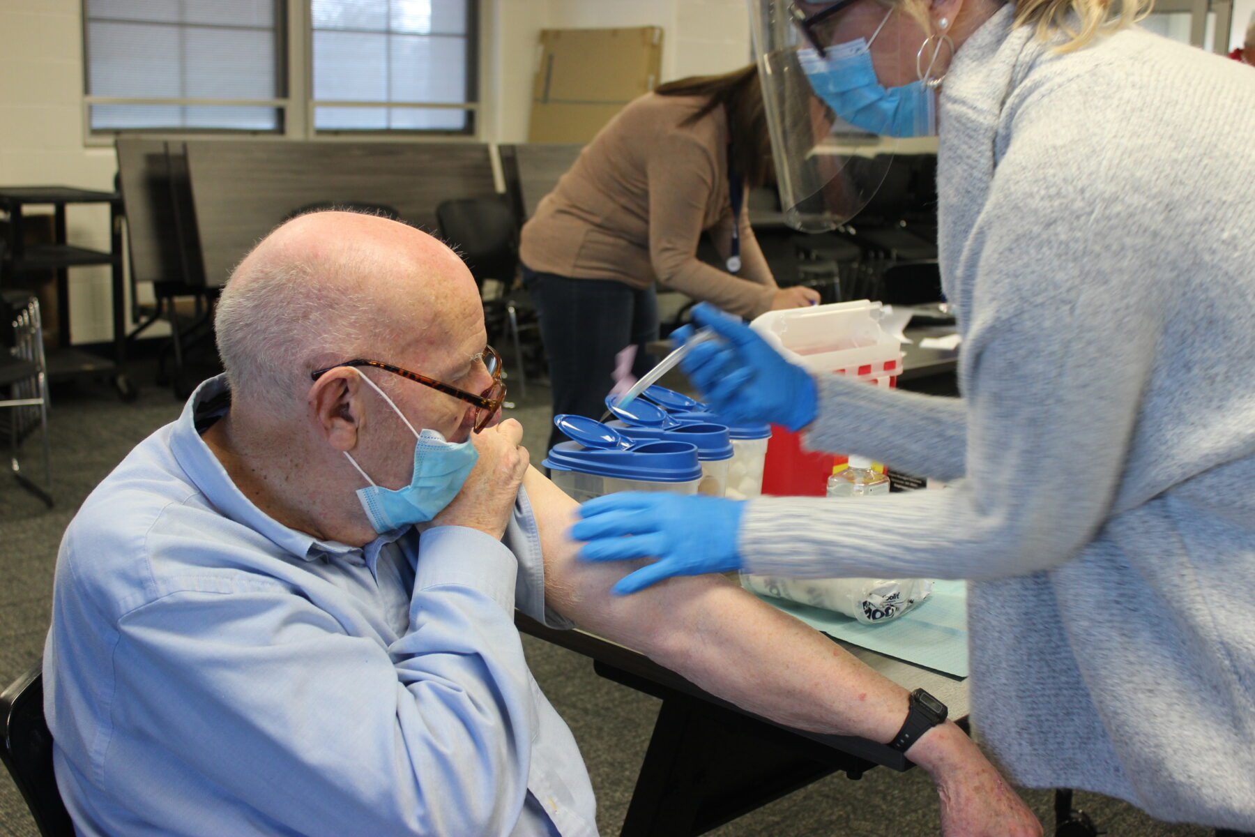 An older man receives an injection from a nurse.