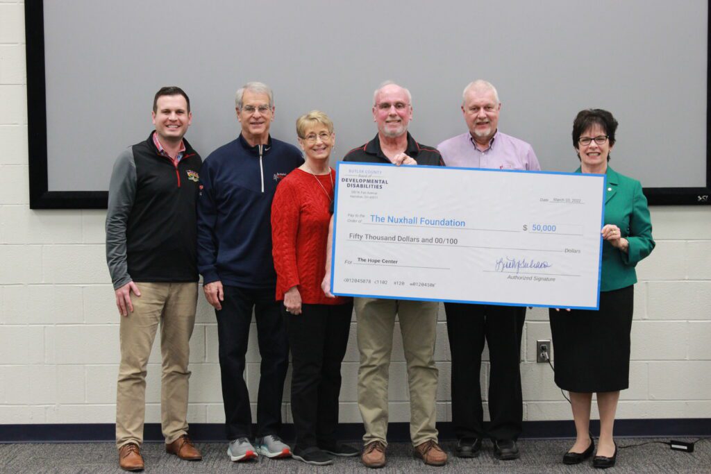 Six people hold a giant check and smile at the camera. The check for $50,000 is made out to the Nuxhall Foundation from the Butler County Board of Developmental Disabilities.