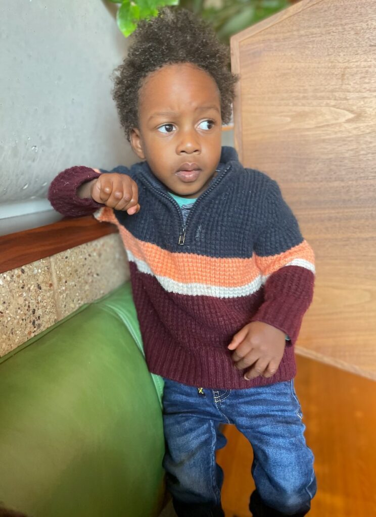 2 year old boy standing by a playset