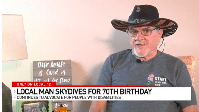 A man in a cowboy hat speaks to the camera. A graphic over the image reads Only on Local 12, Local Man skydives for his 70th Birthday; continues to advocate for people with disabilities. 