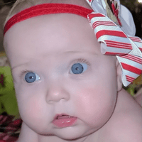 a baby girl with blue eyes and a red head band on
