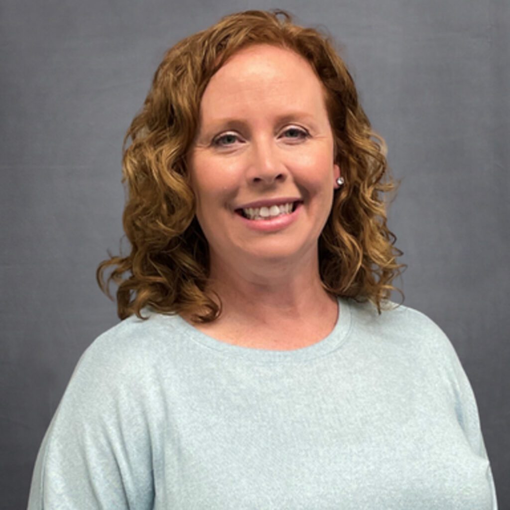 a headshot of a woman in a green sweater with red hair