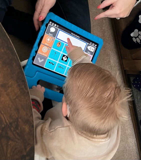 a boy indoors sitting on the carpet touching an iPad