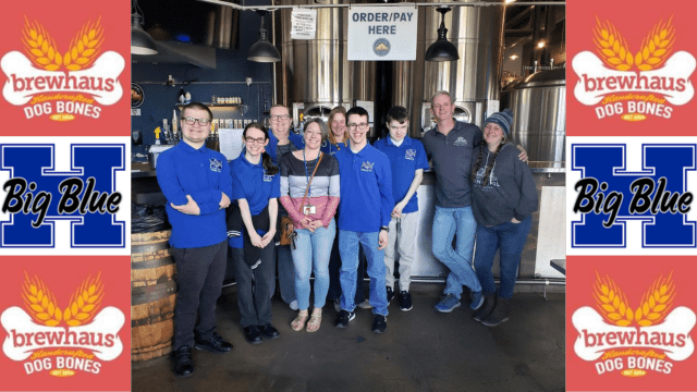 A large group of people standing in a brewery smiling for a photo
