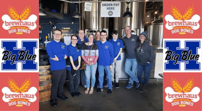 A large group of people standing in a brewery smiling for a photo