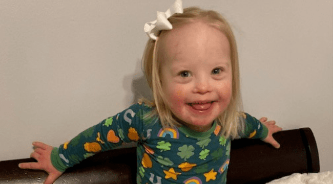 A very joyful toddler aged girl smiles at the camera.