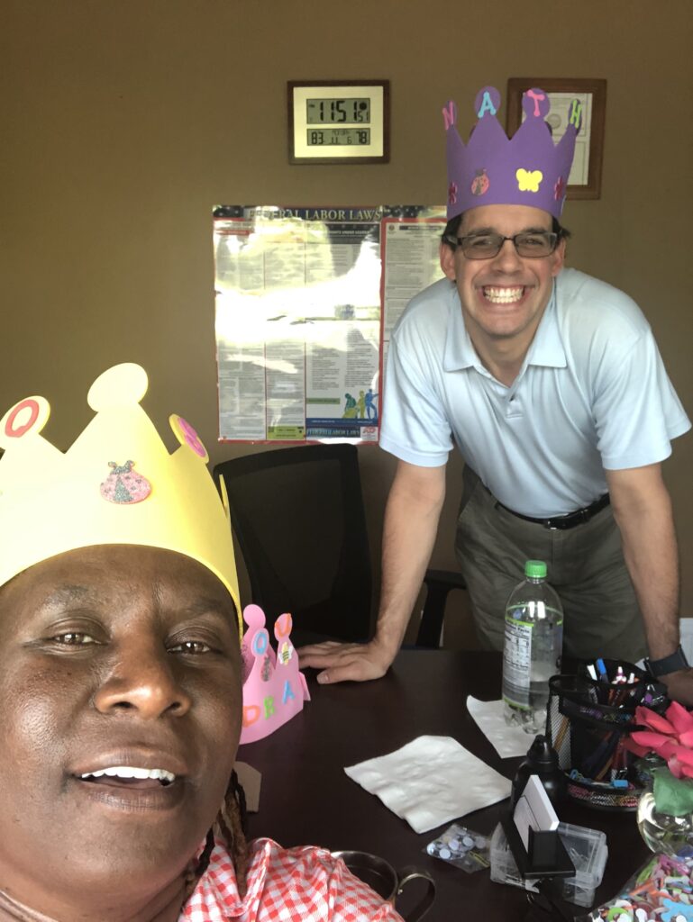 a man and a woman indoors by a desk taking a selfie together.