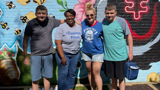 December Community Advocate of the Month: Jackie Nicholson 4 people standing outside in front of a wall of art smiling for a photo