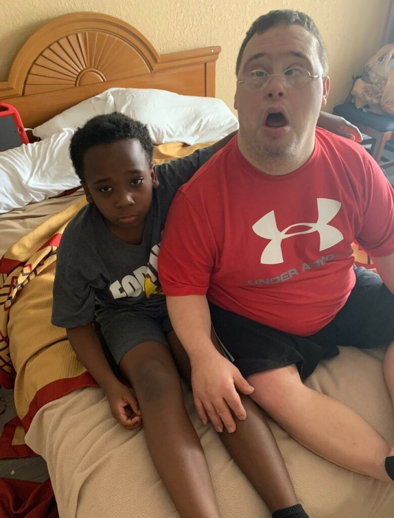 A man and a boy sitting indoors on a bed.