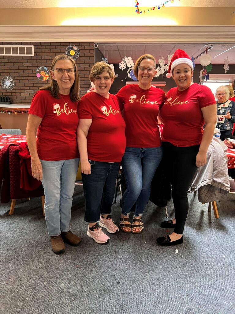 a group of women indoors with Christmas attire on smiling for a photo