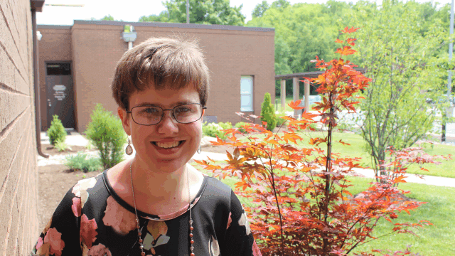 Opinion: Personal Thank You This Week and Always A young woman stands outside on a sunny day. She wears a black floral shirt and glasses. She is smiling directly at the camera.
